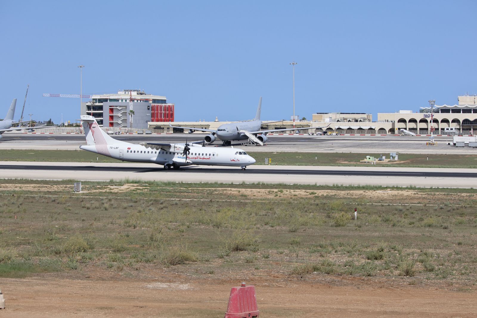 A small turboprop passenger plane on a runway with the Toronto waterfront behind it