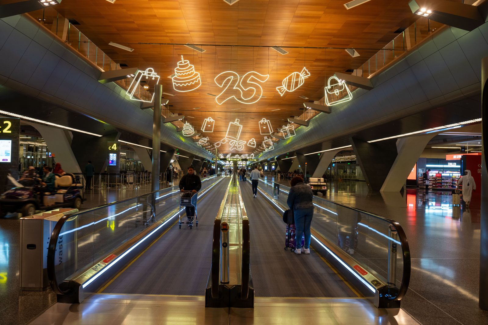 A traveller with a roller suitcase walking through a large airport terminal towards the exit