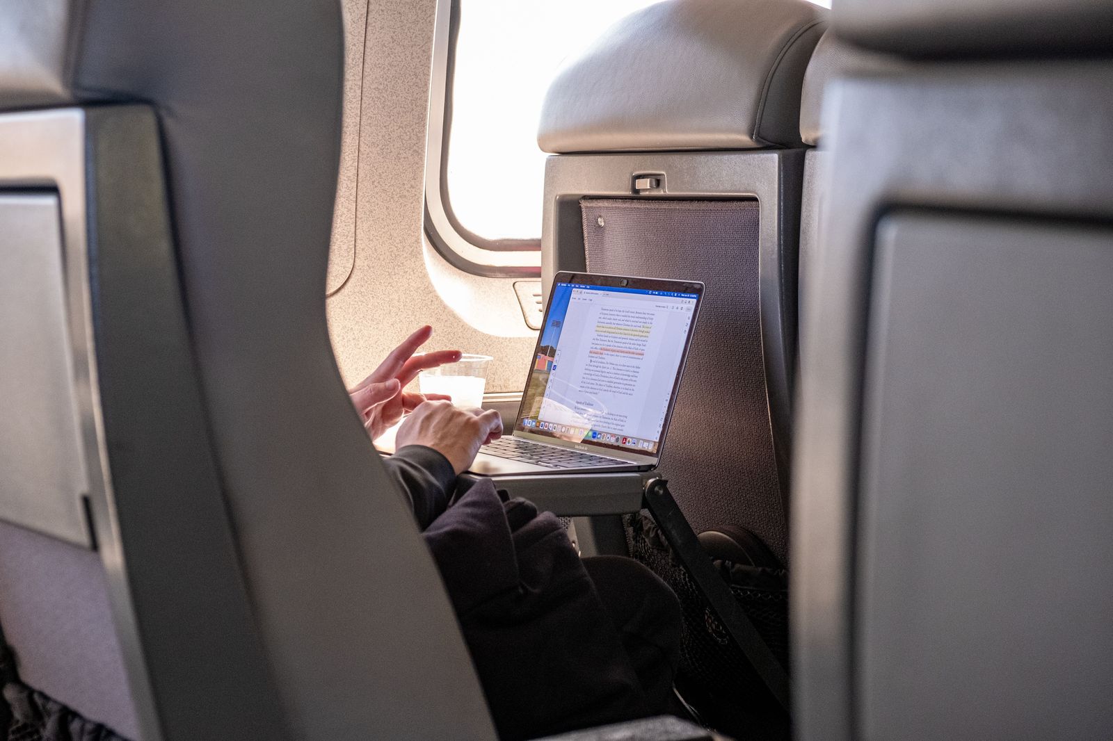 A business traveller working on a laptop in the back seat of a car