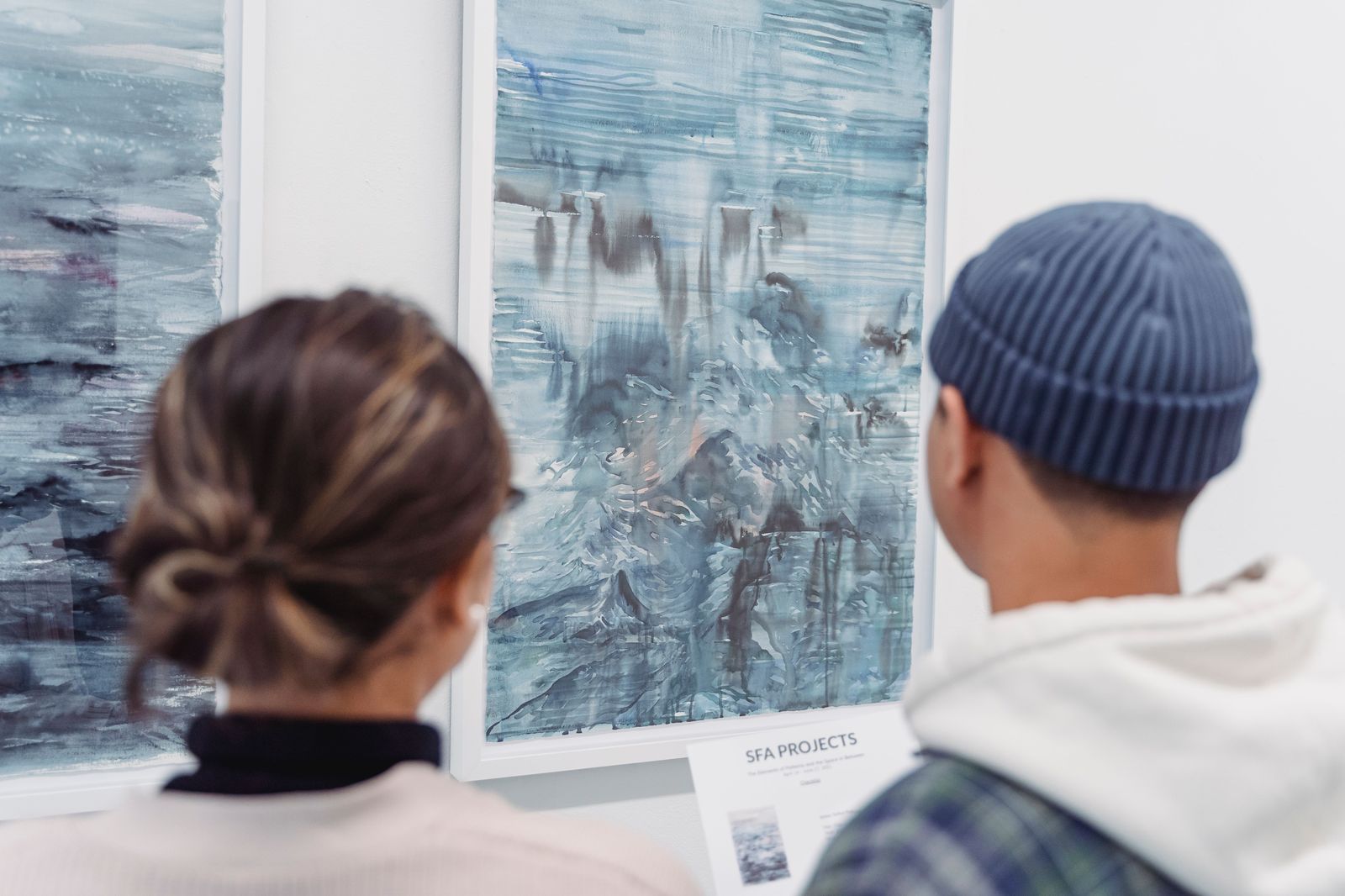 Visitors looking at paintings in a public art gallery