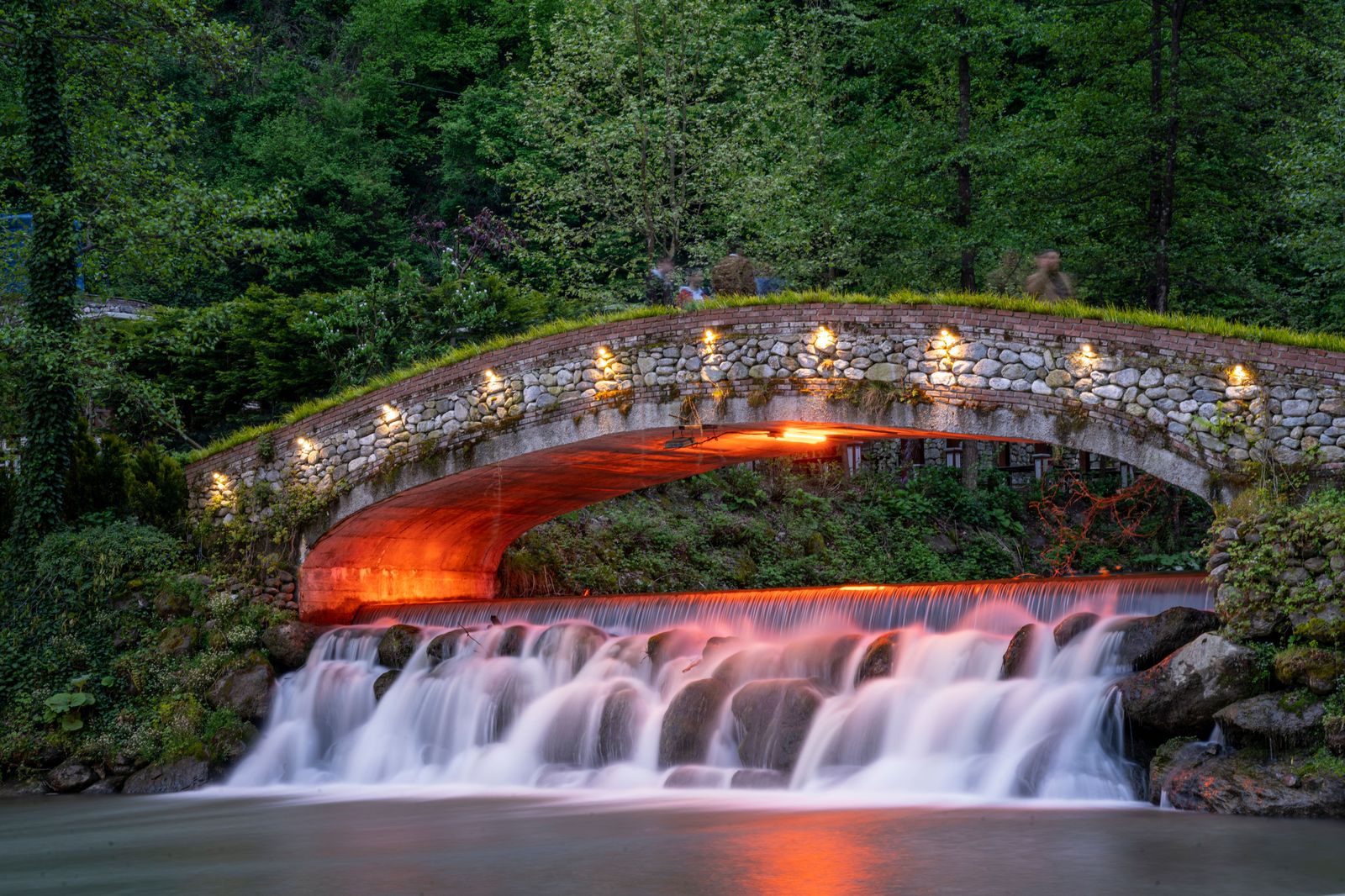 A wide curtain waterfall below a stone footbridge, the classic view at Webster's Falls in Spencer Gorge