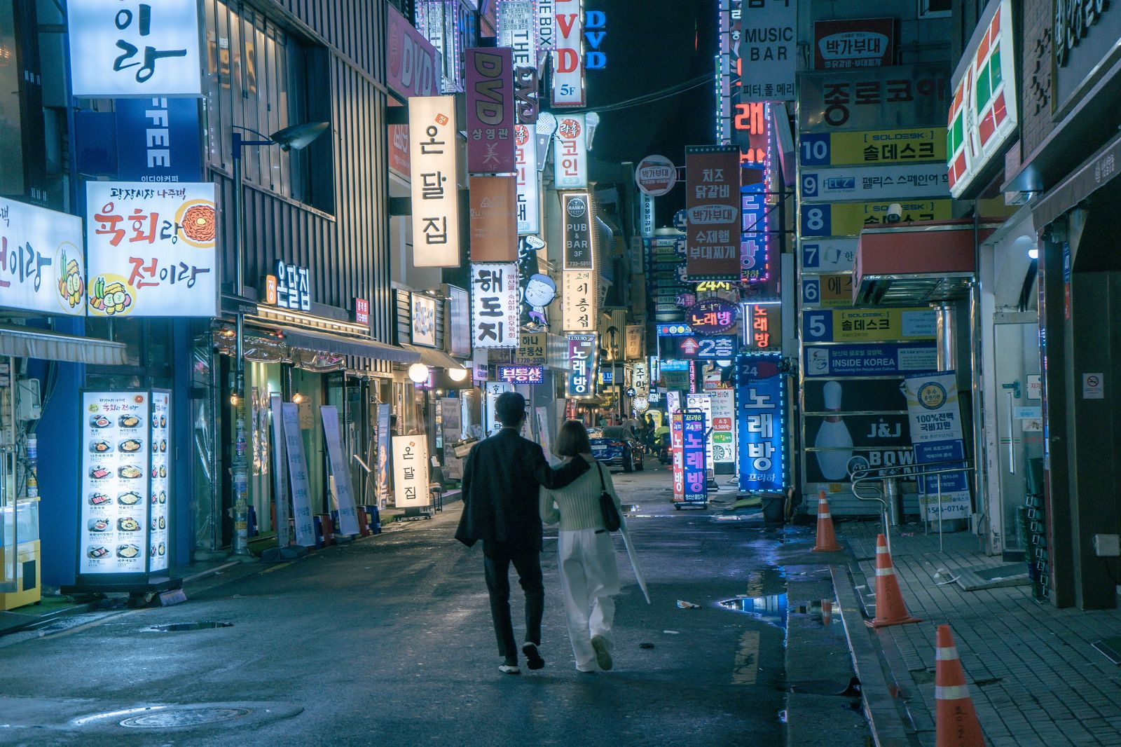 A couple walking along a lit restaurant street on a Hamilton evening