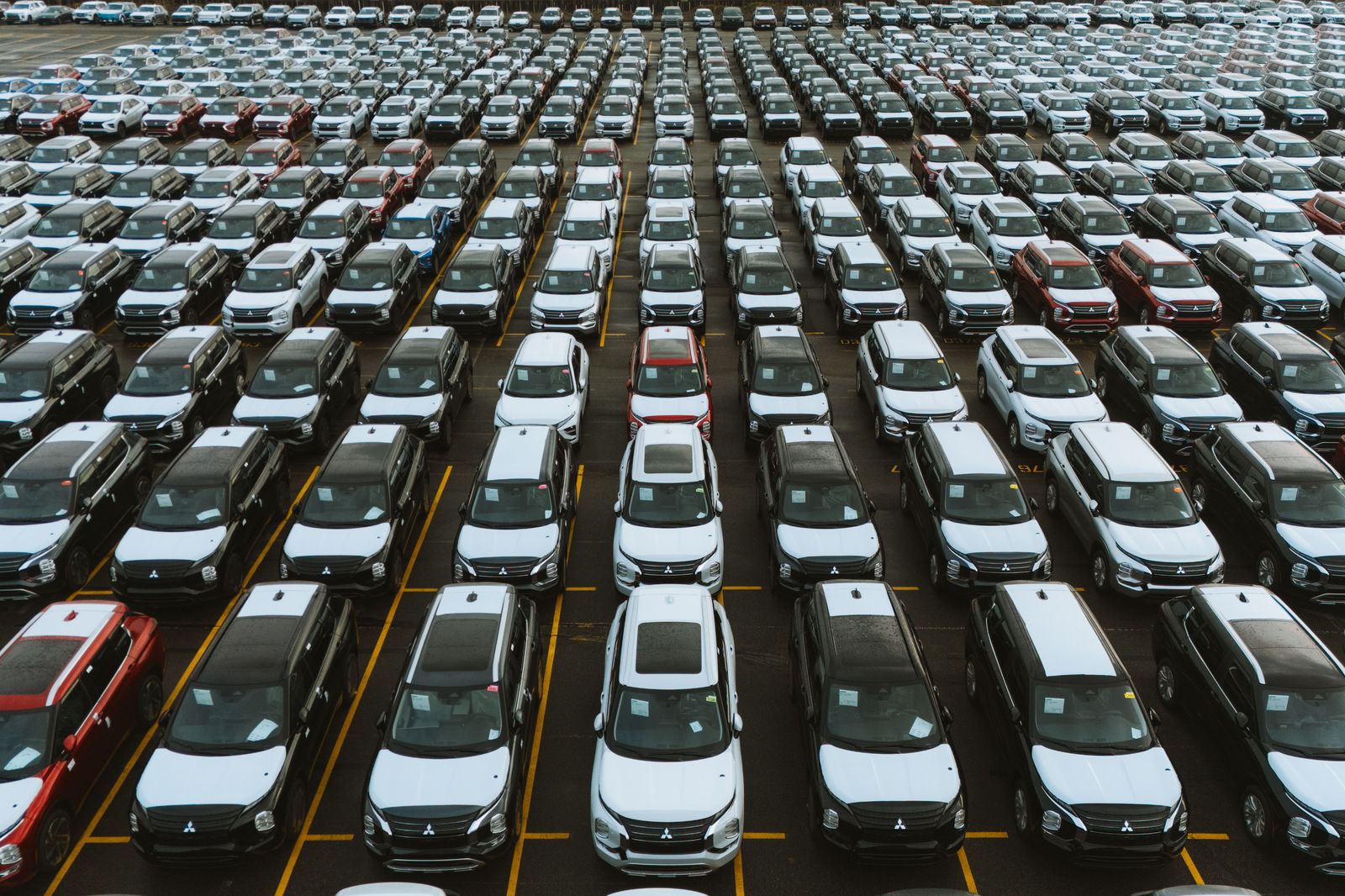 Long rows of parked cars at an airport lot; for a week or more away, the daily rate adds up fast.