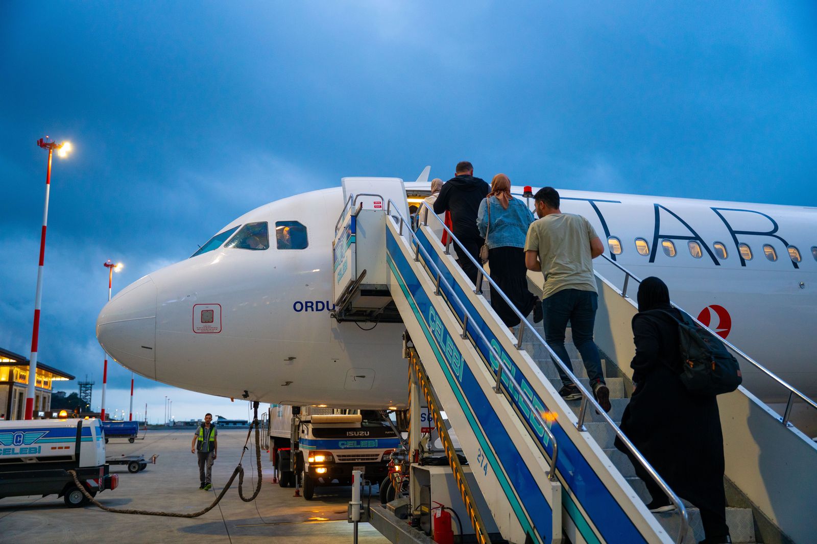 An evening airport curb; booked cars load at the commercial pickup area, not the general arrivals lane.