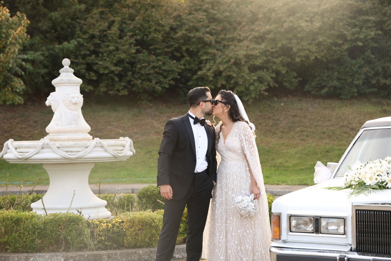 A wedding couple beside a white stretch limousine on their wedding day