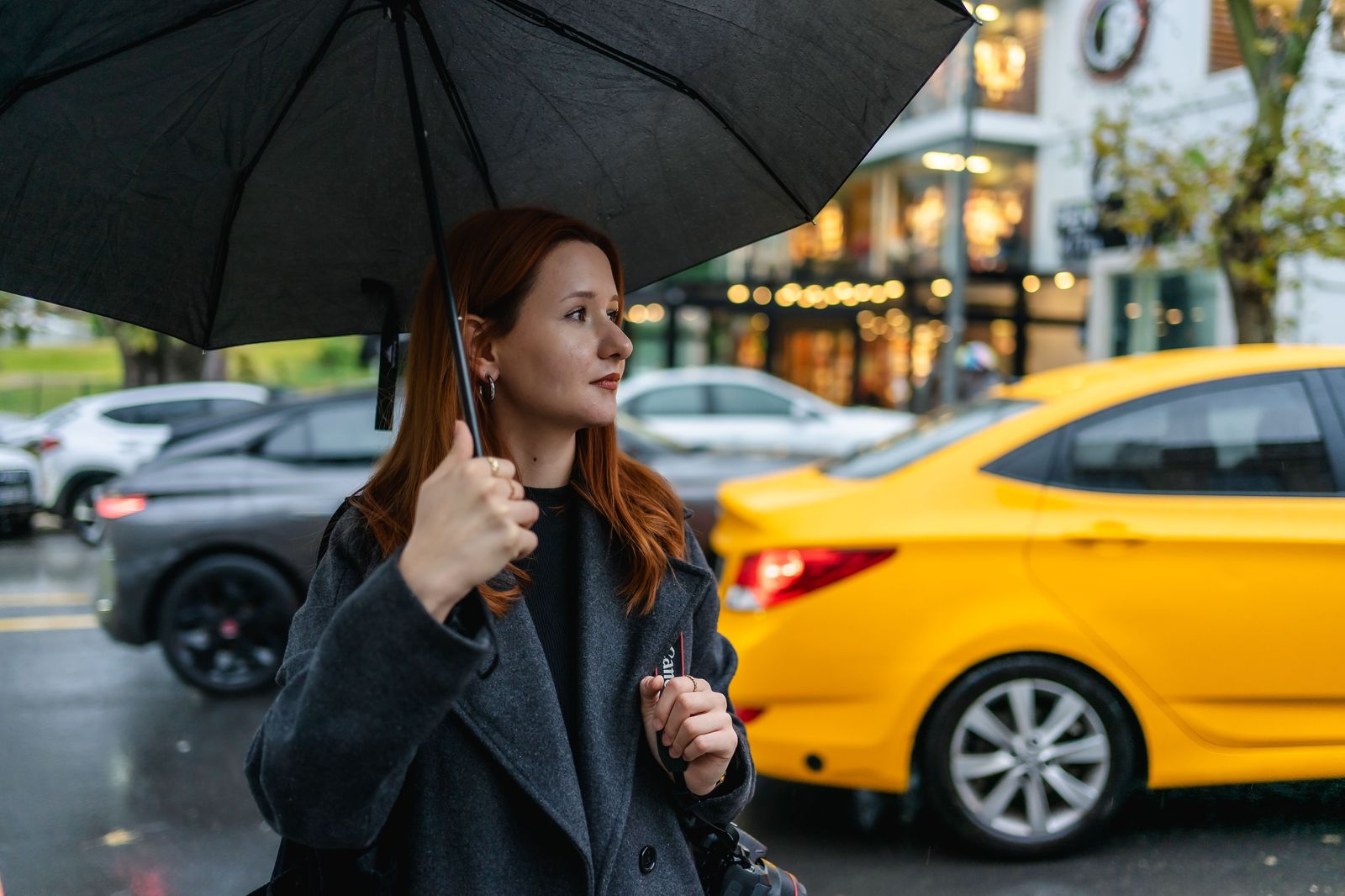 A chauffeur holding an umbrella at the car door for an executive in the rain