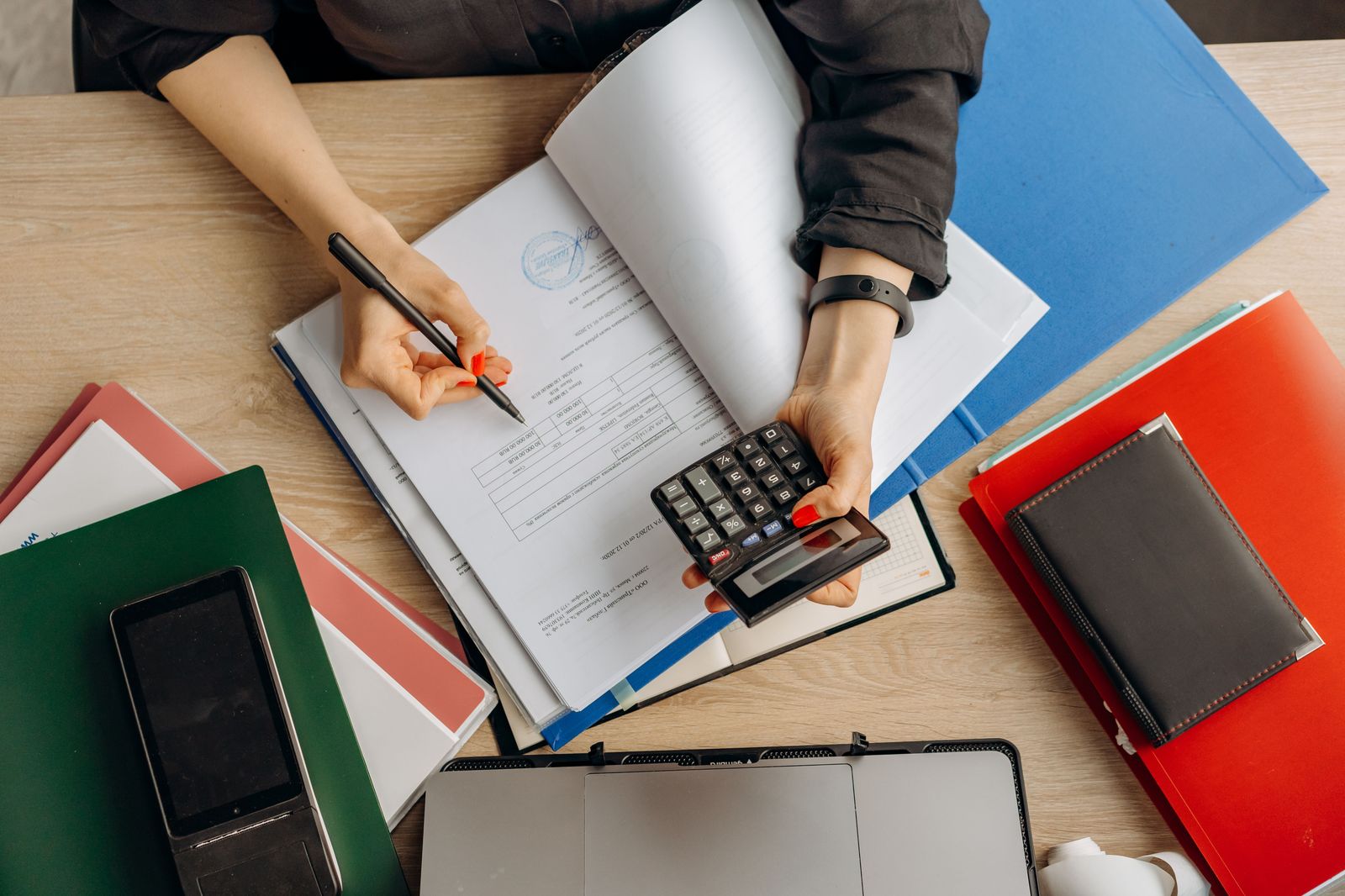 Invoices and a calculator on a desk, reconciling a month of car service trips