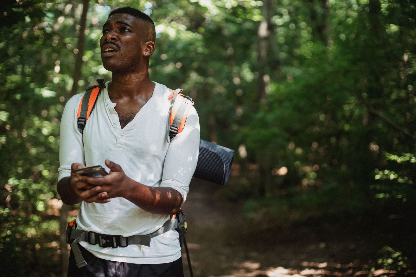 A hiker checking a map on a phone on a forest trail