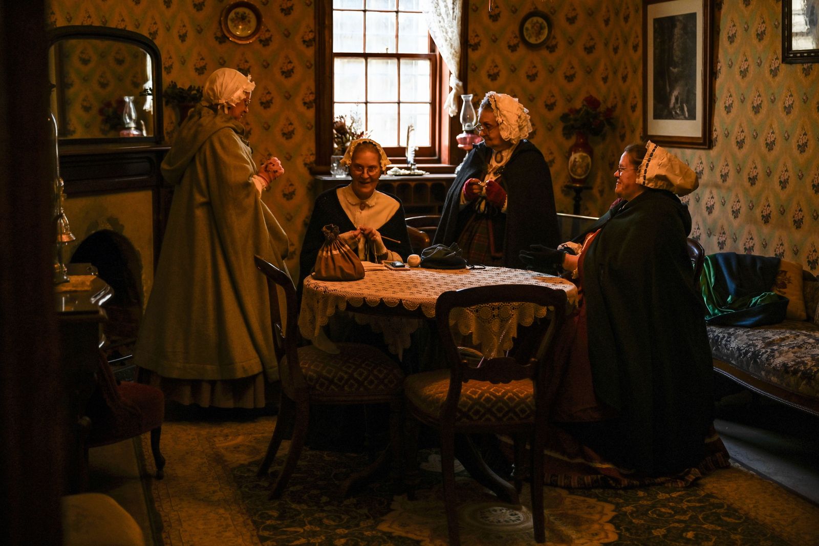 A costumed guide leading visitors through the rooms of a historic house