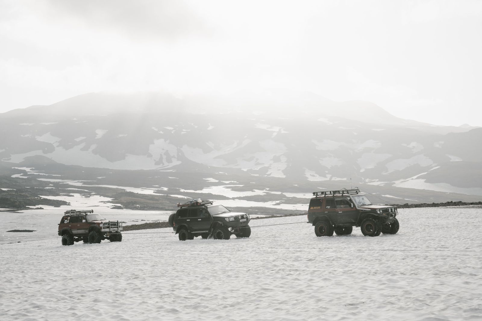 A black SUV driving along a snowy highway in winter