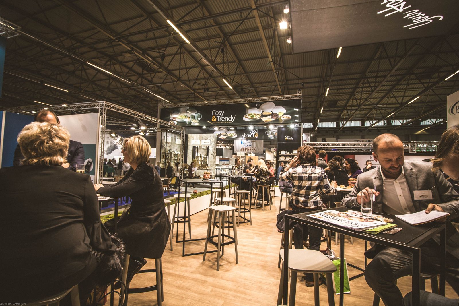 Exhibitors at a booth in a busy trade show hall