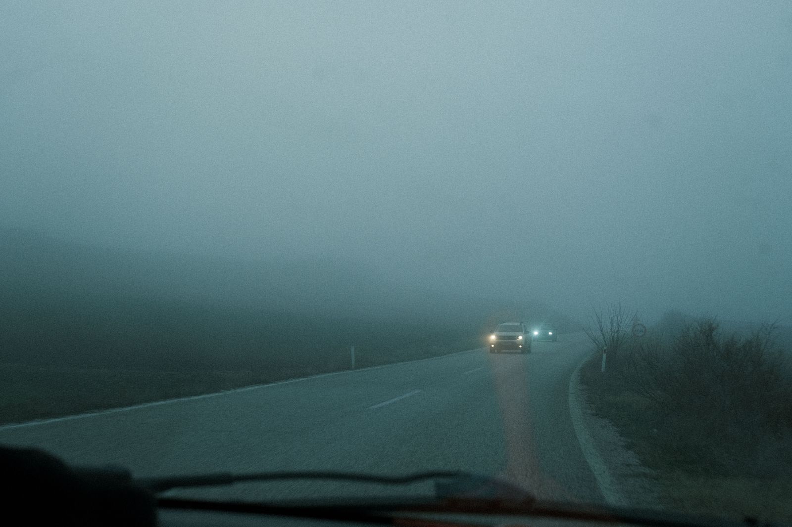 Car headlights on a dark highway in the early morning before a flight
