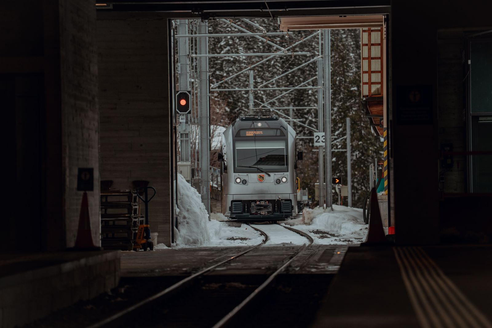 A commuter train leaving a lit platform late at night
