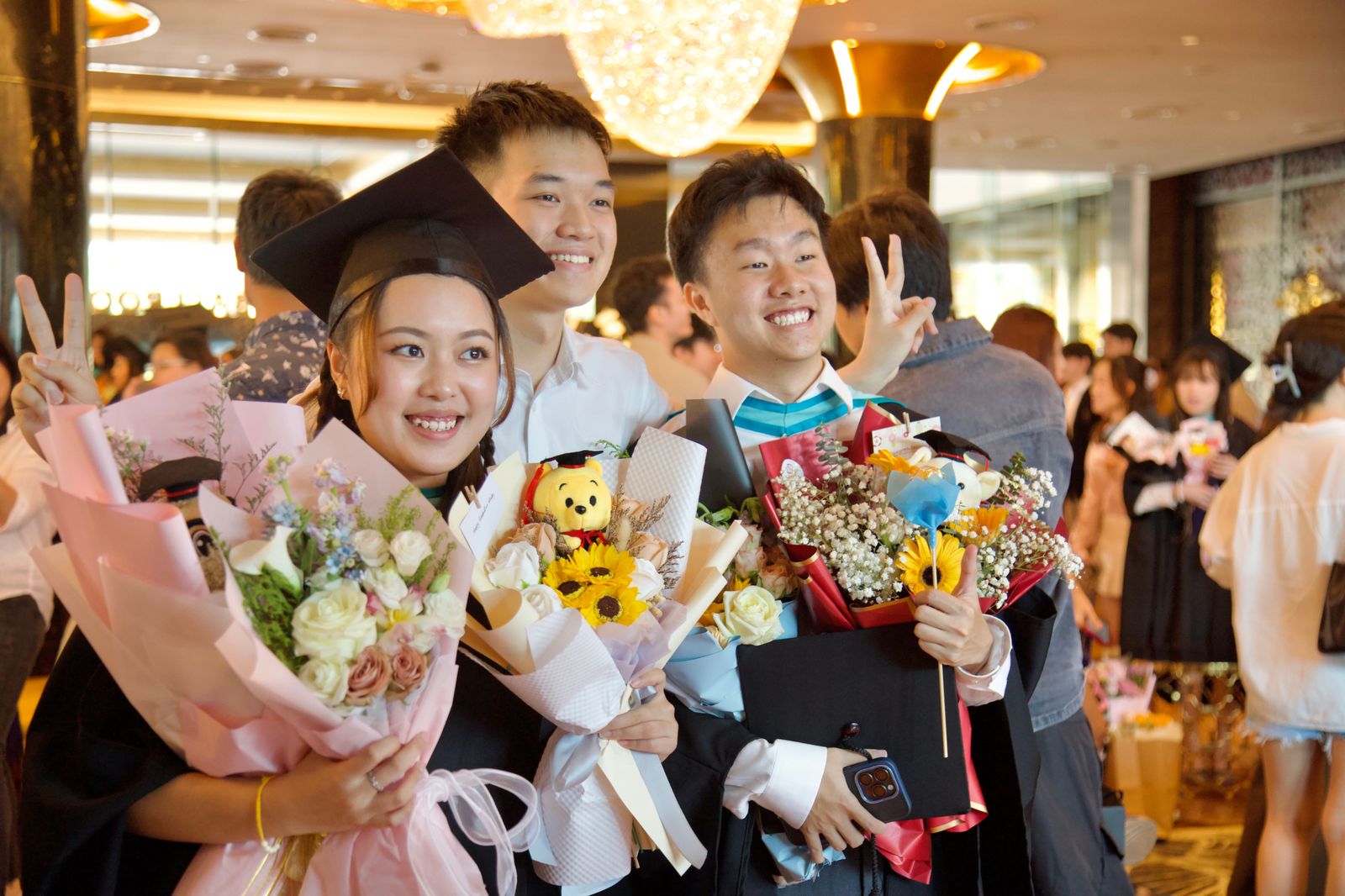 A graduate holding flowers with family after a ceremony