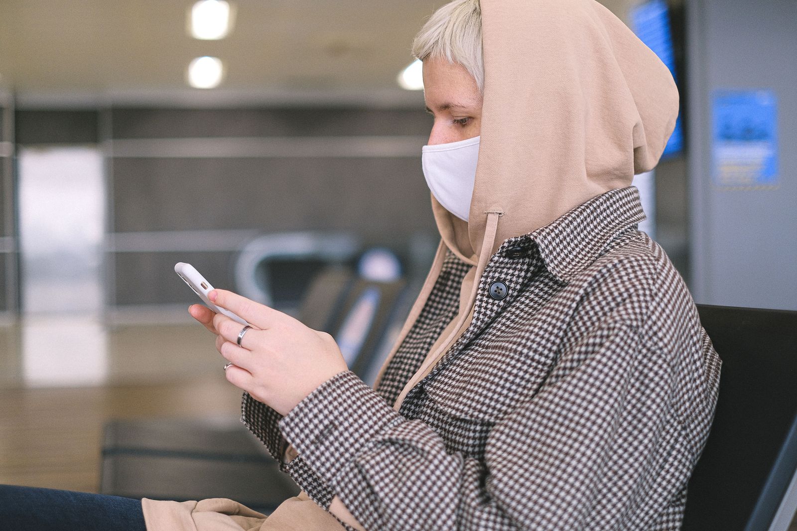 A traveller texting on her phone in an airport terminal while waiting for her bags