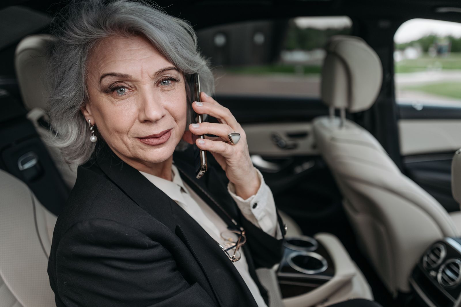 A businesswoman working on a laptop in the back of a car