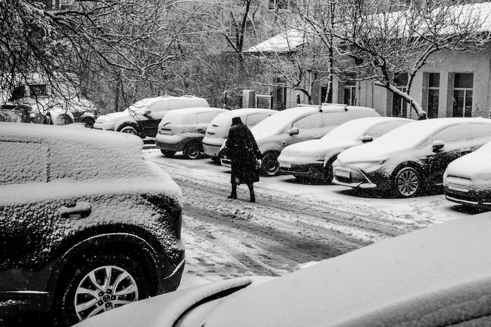 A snow-covered car in an outdoor parking lot after a week away