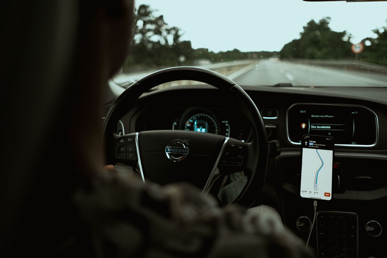A driver checking a traffic map on a phone mounted in a car