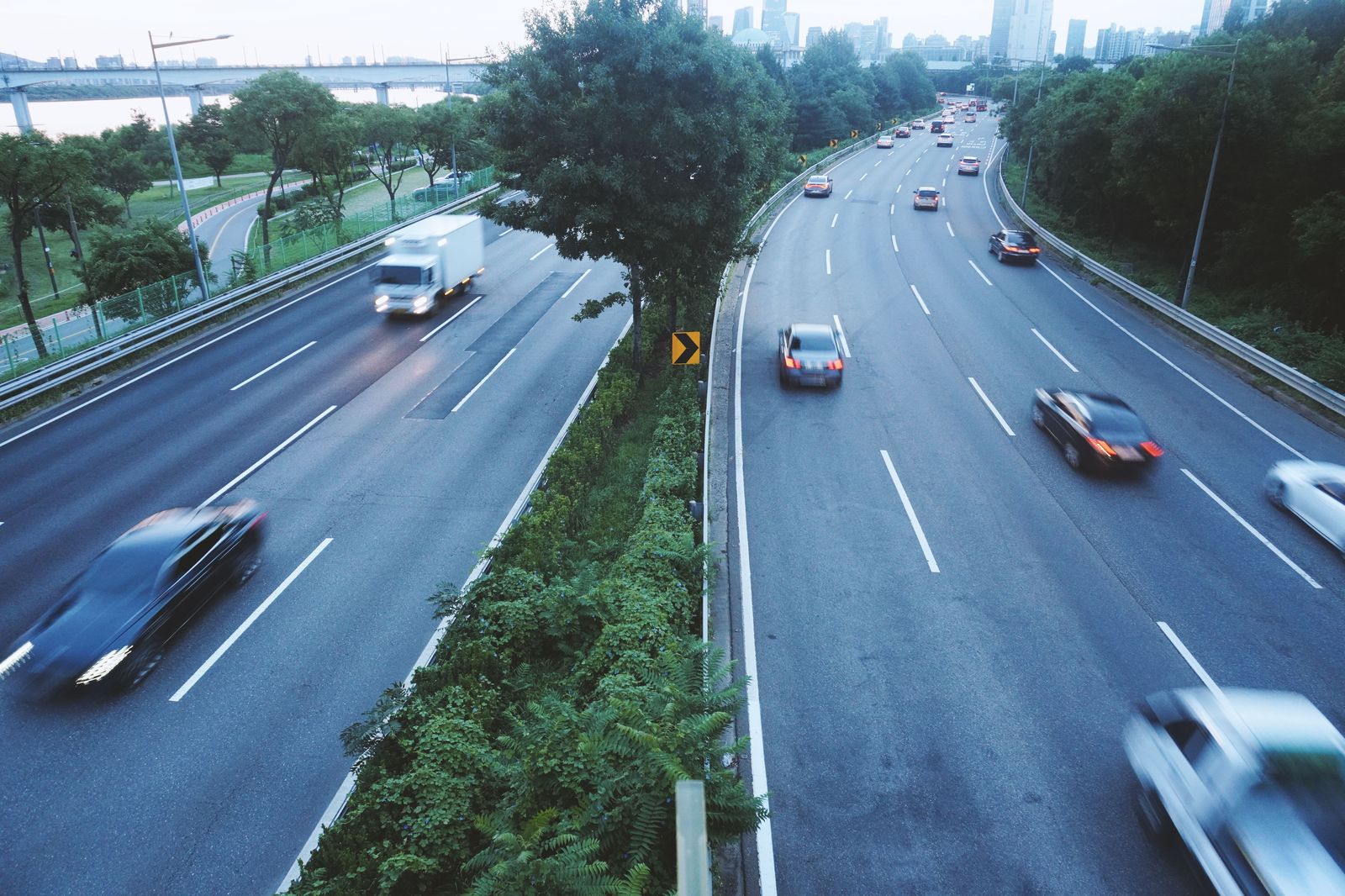 Evening traffic moves along a multi-lane highway toward a border bridge