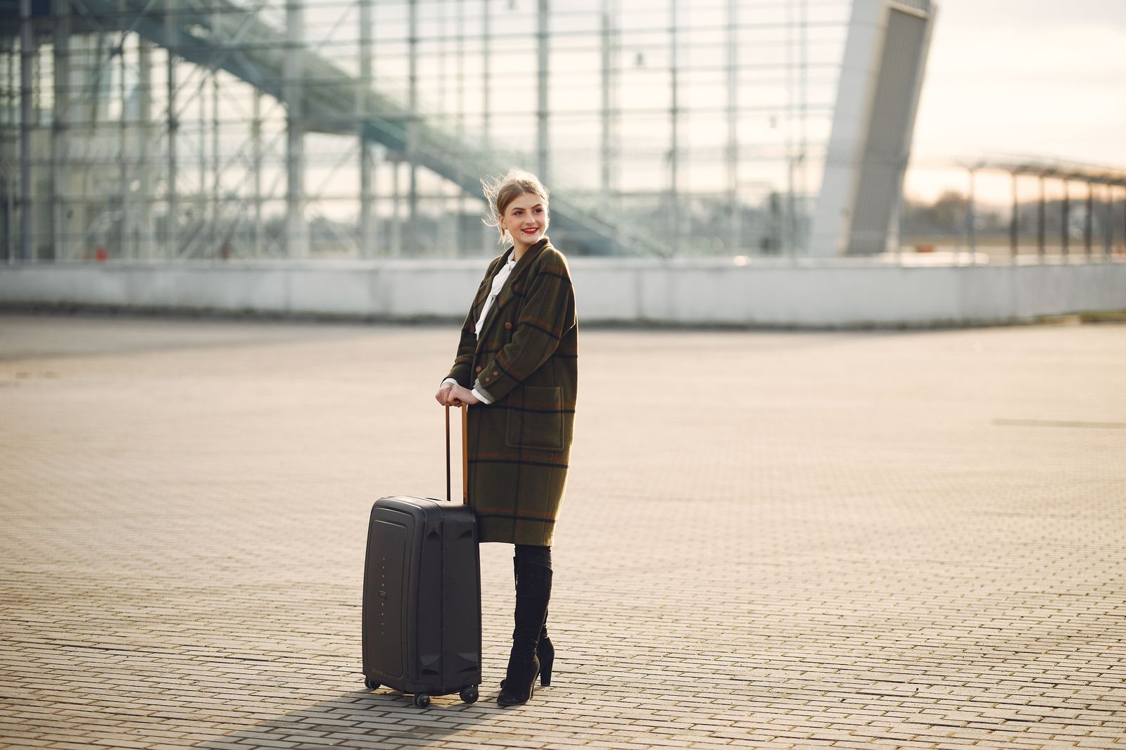 A student with two large suitcases walking through an airport arrivals hall
