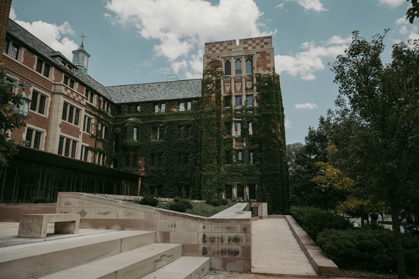Students walking between stone university buildings on an autumn afternoon