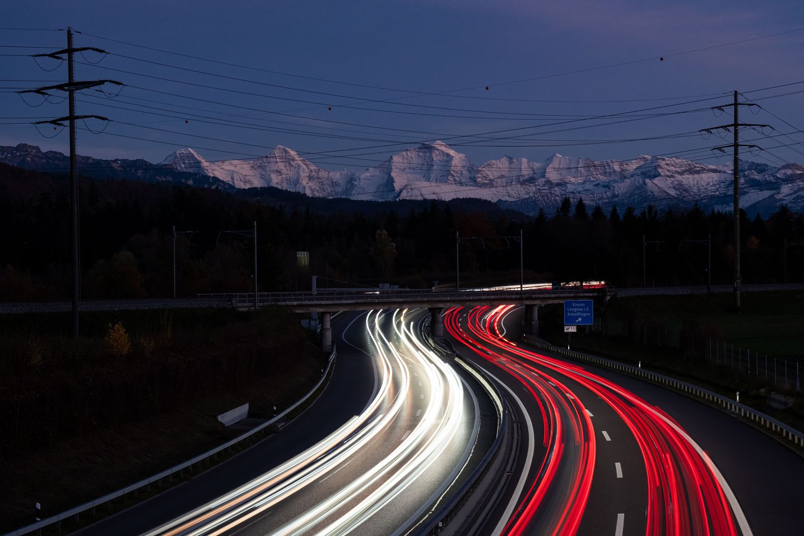 Cars and trucks on a snowy highway at night with headlights glowing