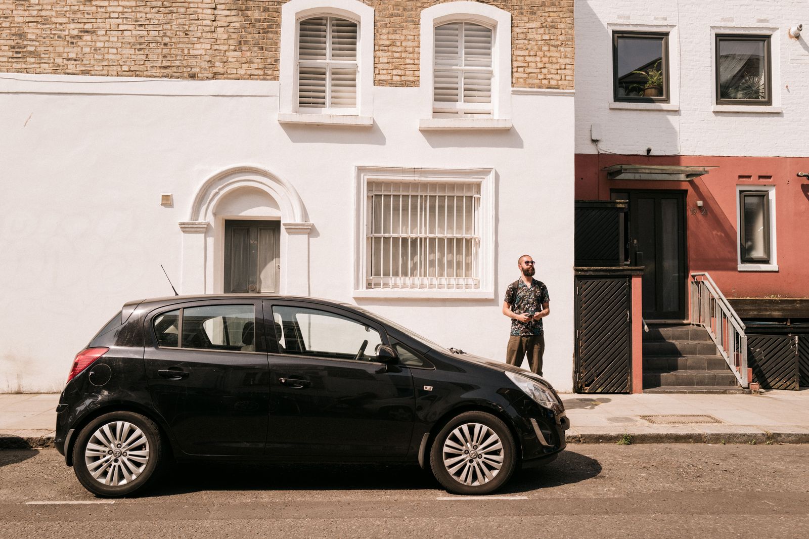 A chauffeur standing beside a black car, waiting to confirm the itinerary with parents before prom