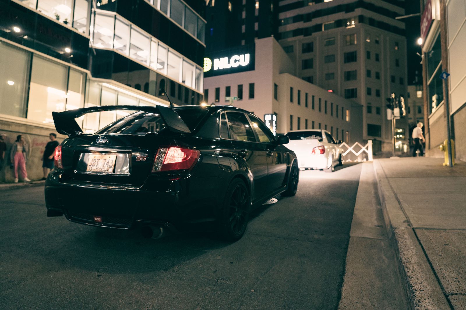 Black sedan waiting on a quiet side street near a downtown arena after a show