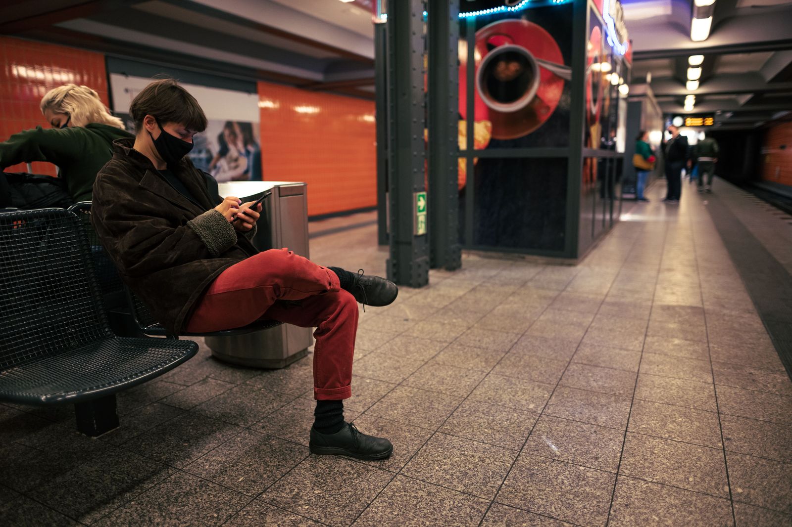 A traveller with a suitcase checking a phone message while walking toward a station exit