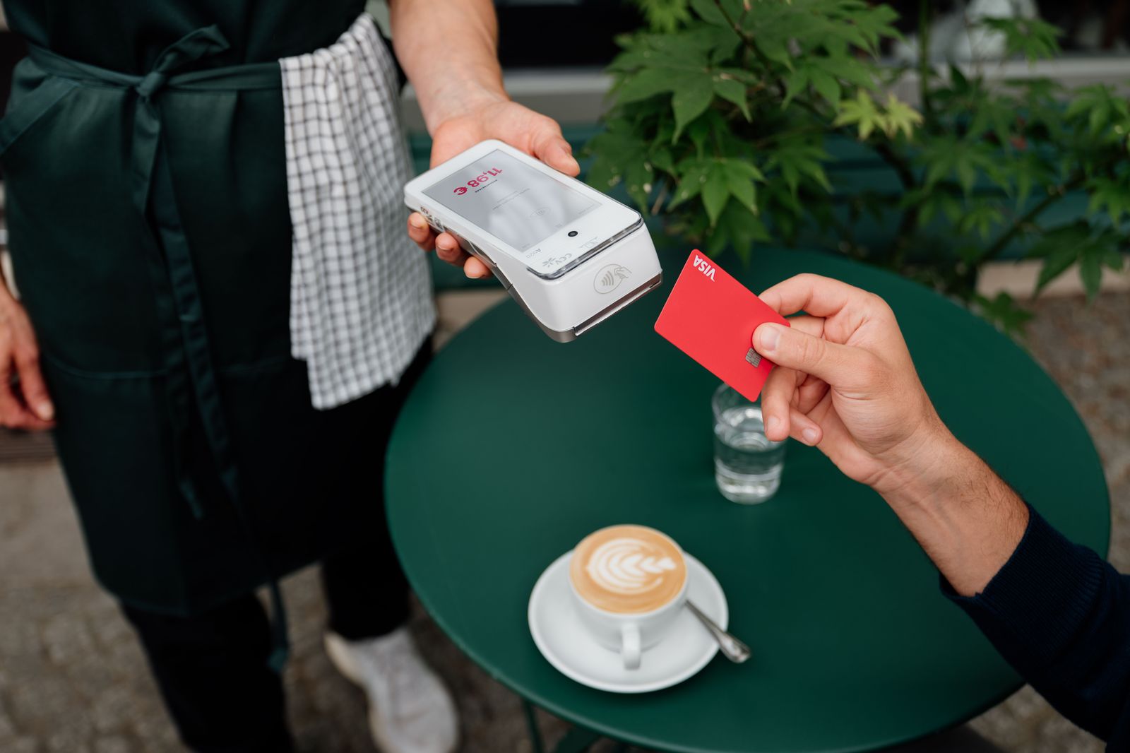 A customer taps a card on a payment terminal at a cafe counter
