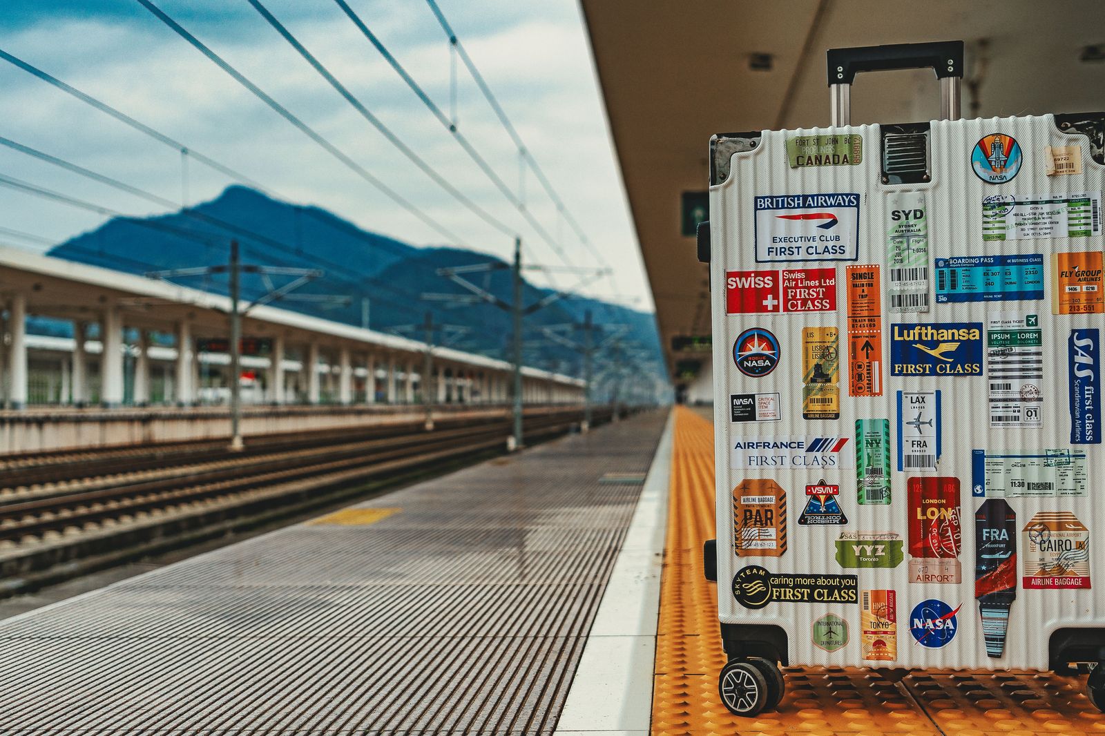 A traveller wheeling a small suitcase along a quiet station platform
