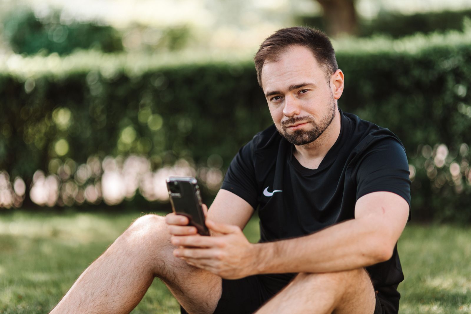 Man checking his phone on a quiet street while waiting for a ride home