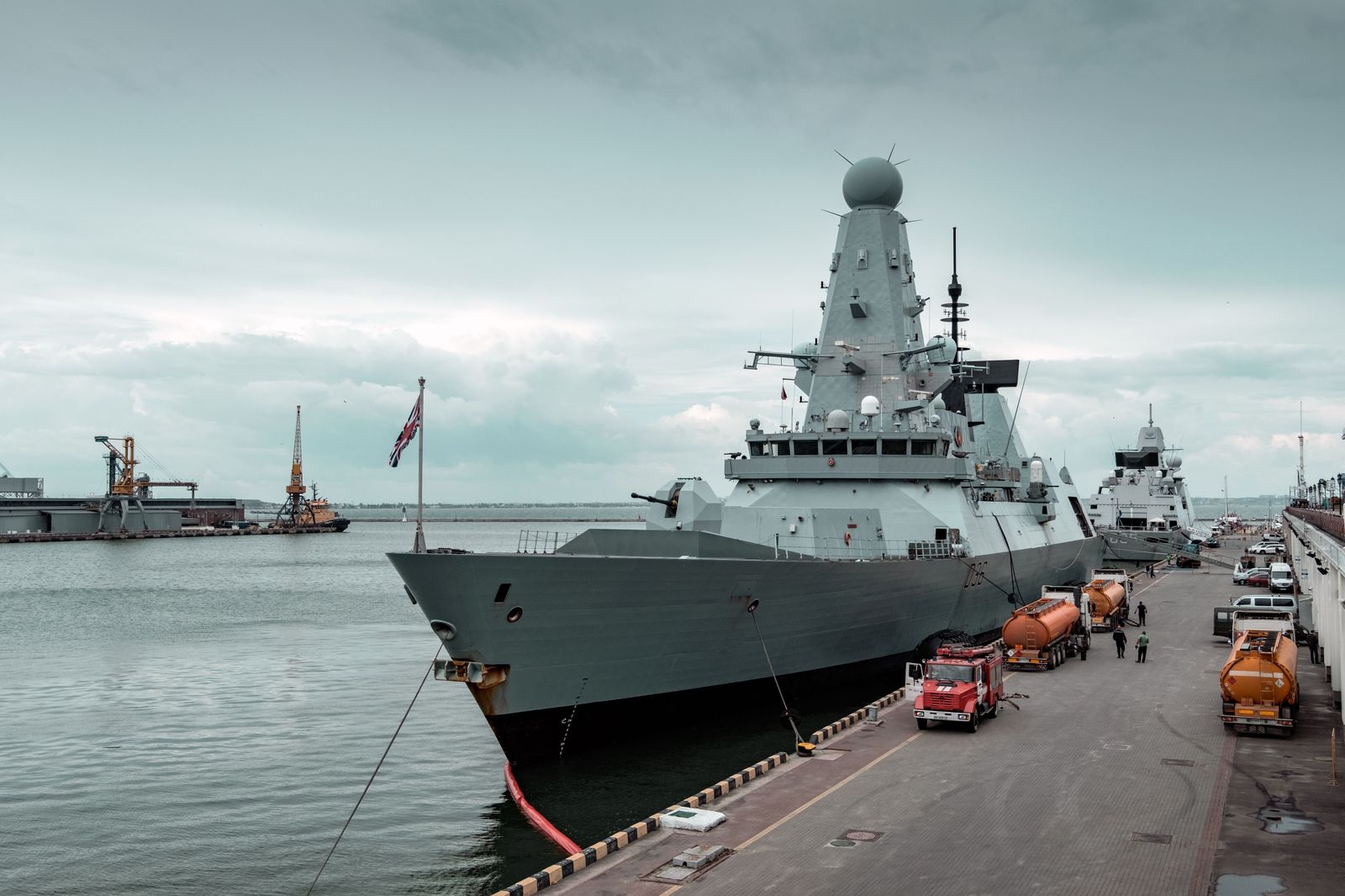 A grey naval destroyer moored as a museum ship at a harbour pier