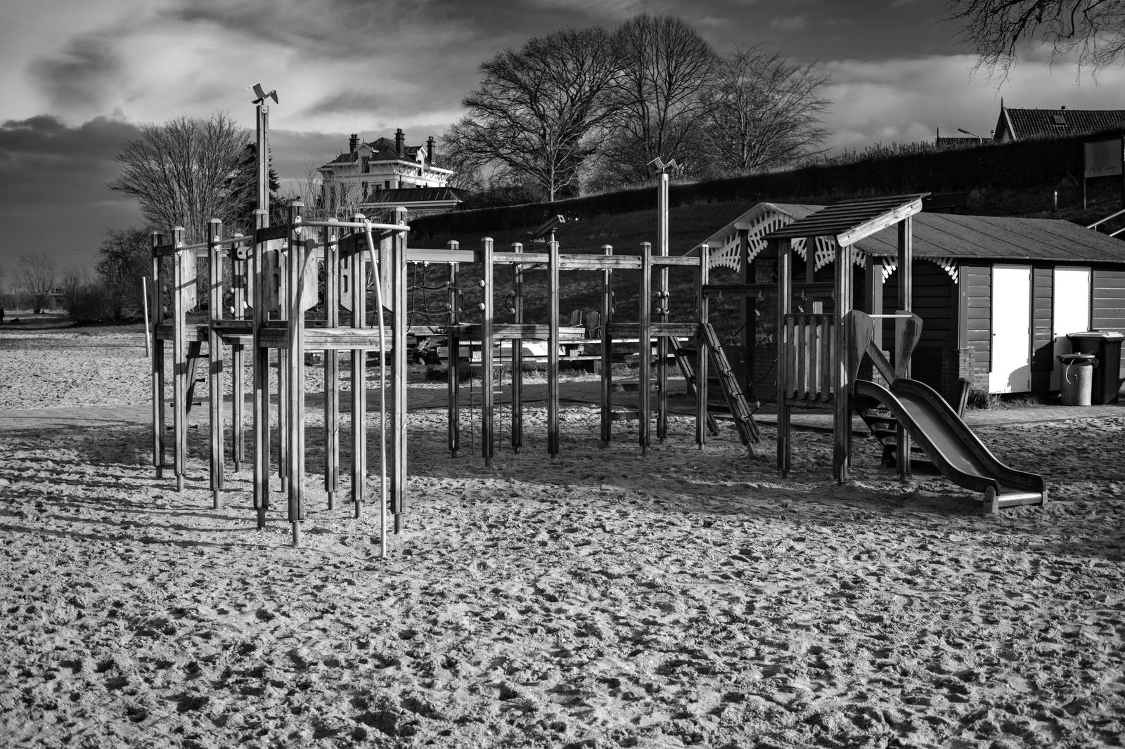 Children playing in a waterfront park playground near a small beach
