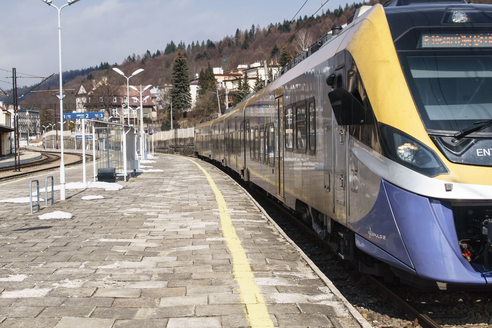 A car stopping briefly at a station drop-off area as a passenger gets out