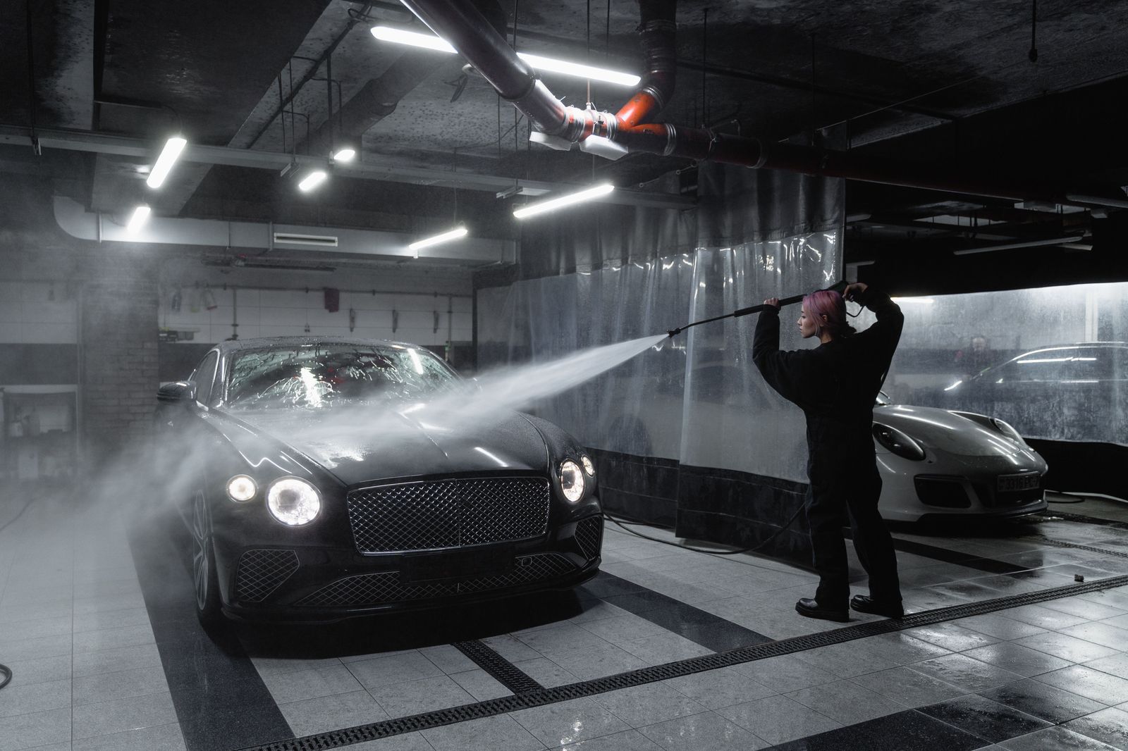 A chauffeur cleaning the exterior of a black sedan before the first pickup of the day