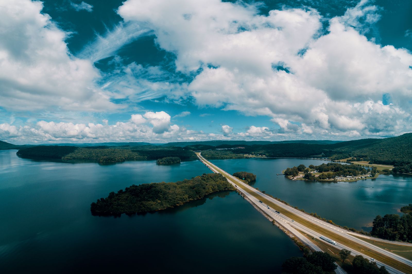 A highway curving toward a lake and a bridge on a clear day