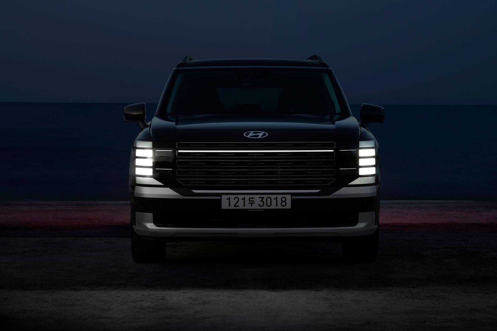A black SUV waiting at a hotel entrance in the early evening
