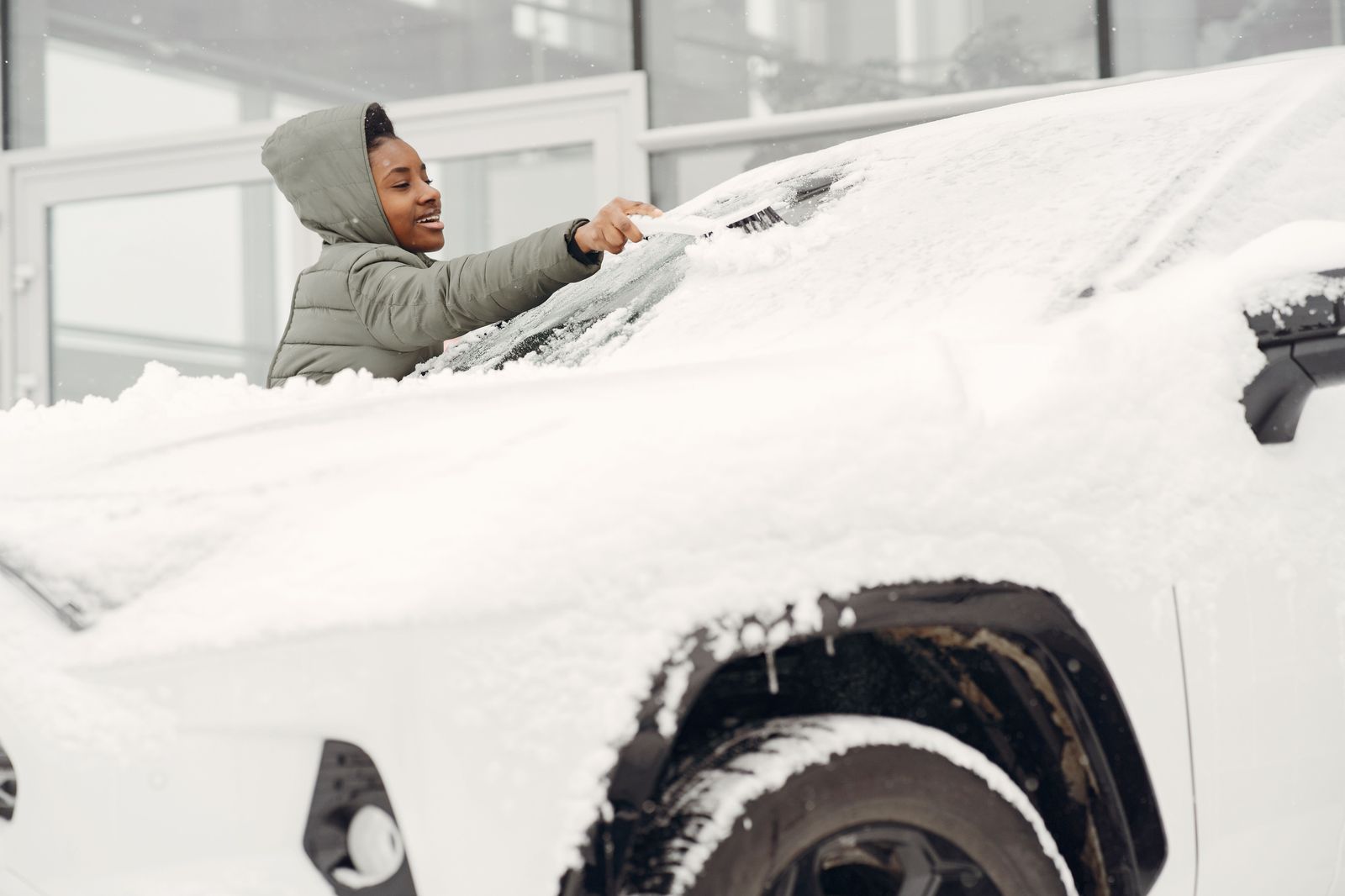 A snow-covered car windscreen in an airport parking lot after a winter trip