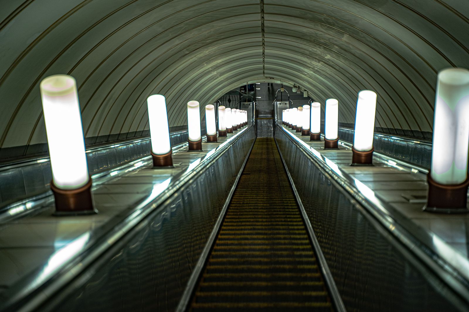 A long moving walkway in a brightly lit underground pedestrian tunnel