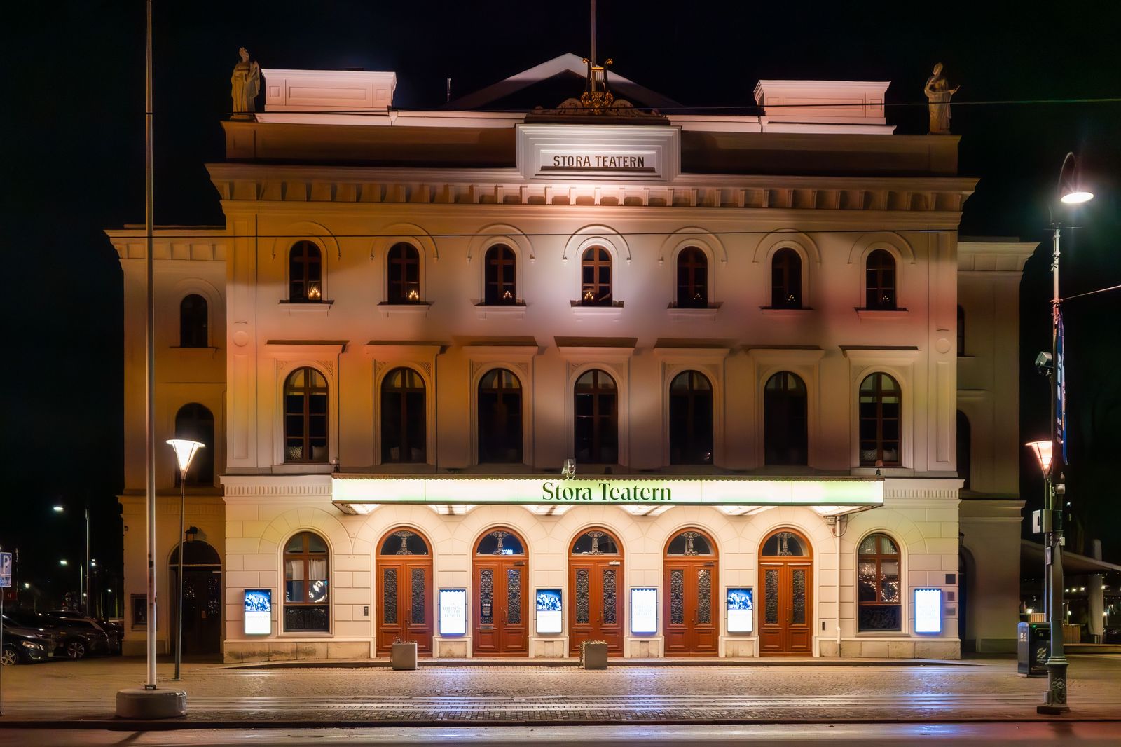 A theatre lit up on a show night in downtown Brampton; an hourly car waits nearby for the ride home.