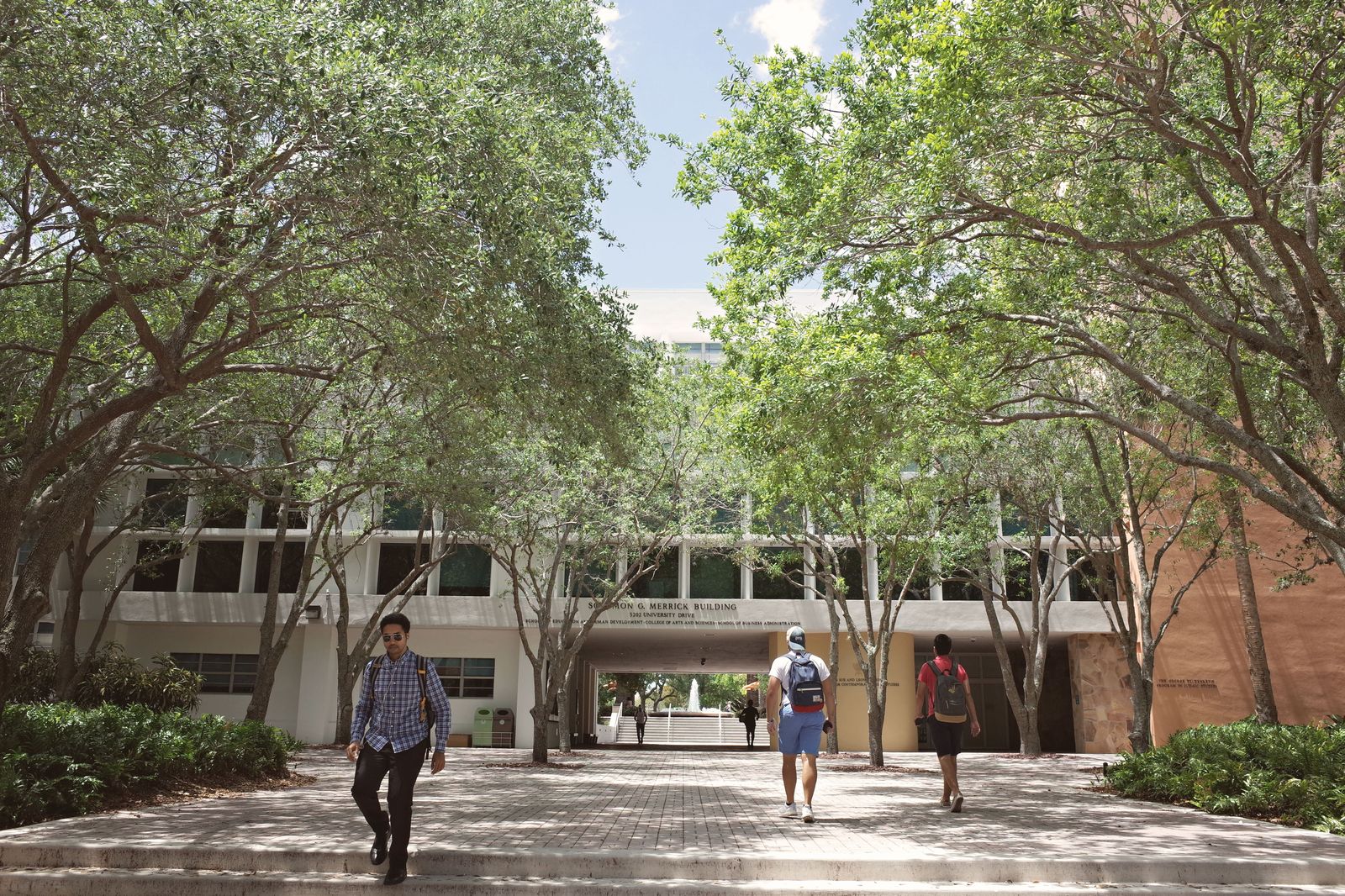 Students walk across a college campus on move-in weekend, when families book vans from the airport.
