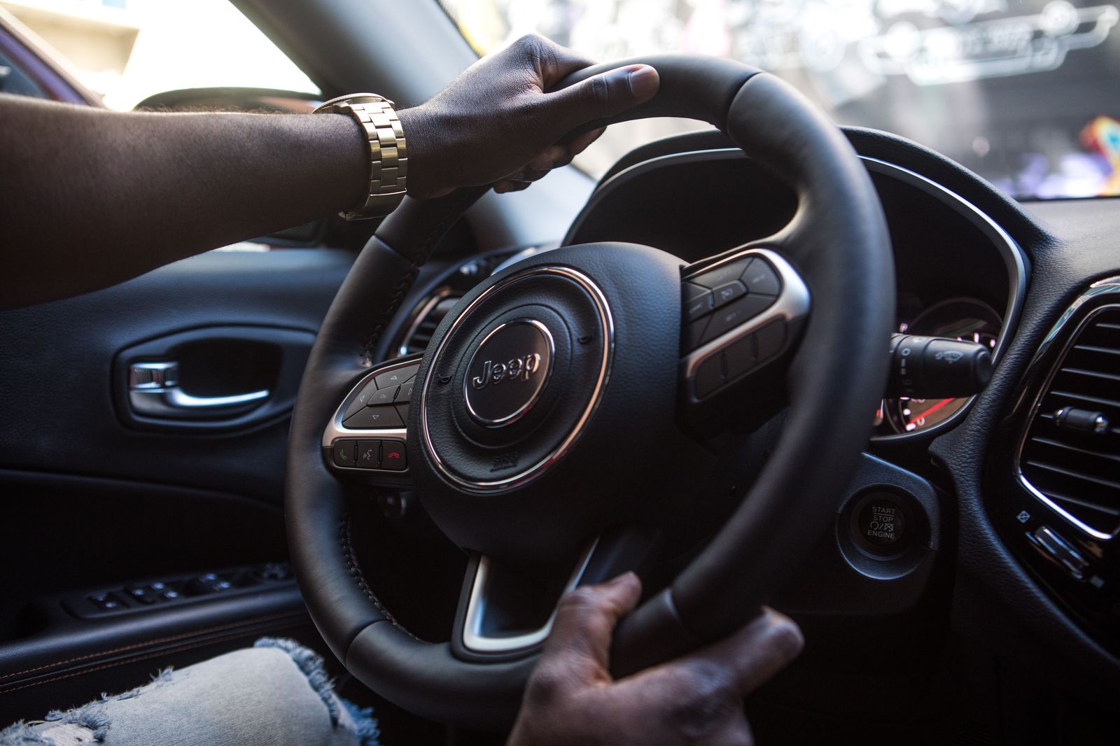 A chauffeur's gloved hands on the steering wheel of a luxury sedan