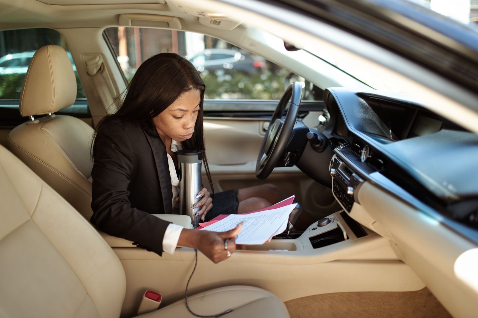 A businessman working on a laptop in the back seat of a chauffeured car
