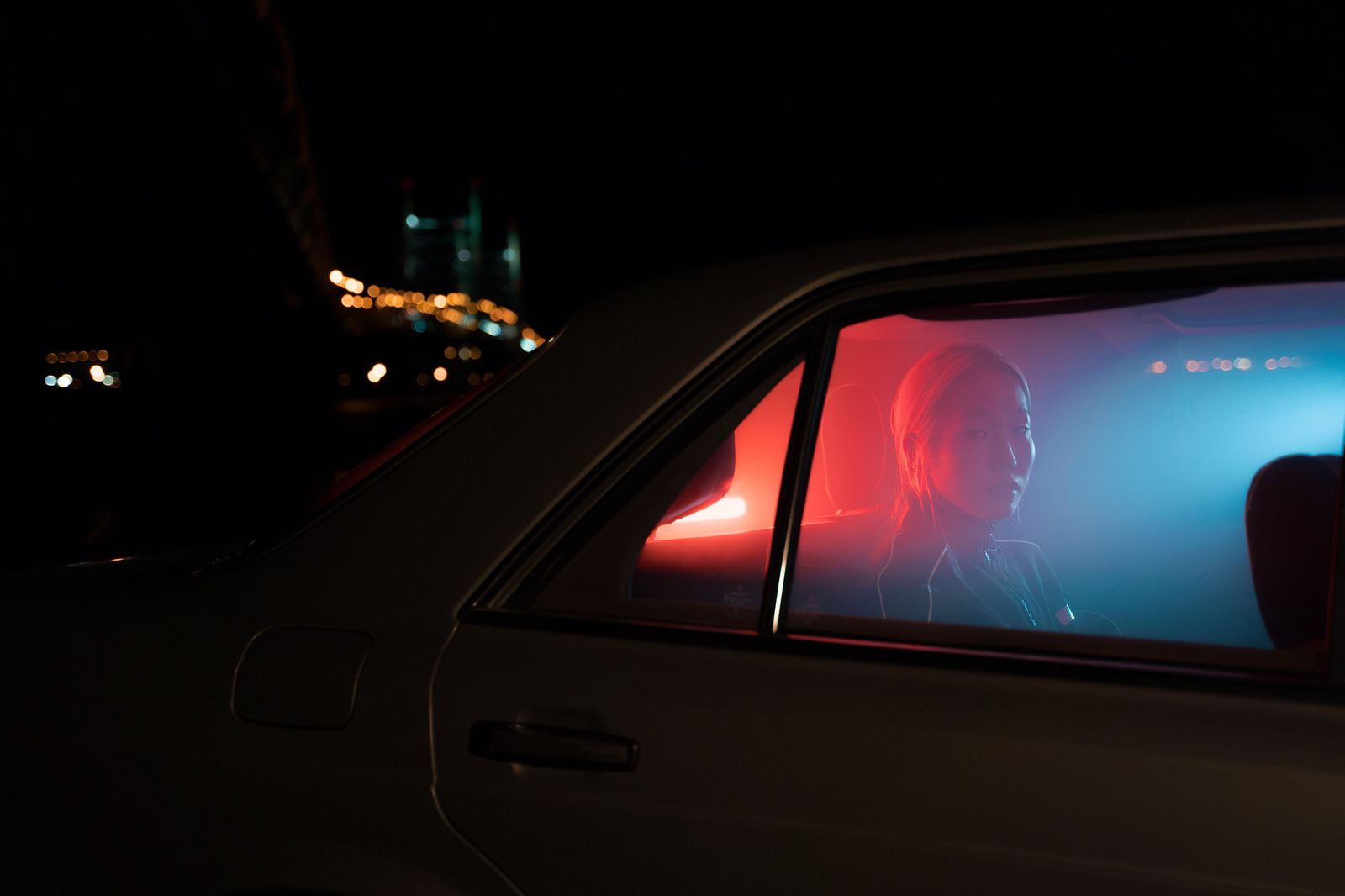 A passenger relaxing in the back seat of a black sedan on the QEW toward Toronto