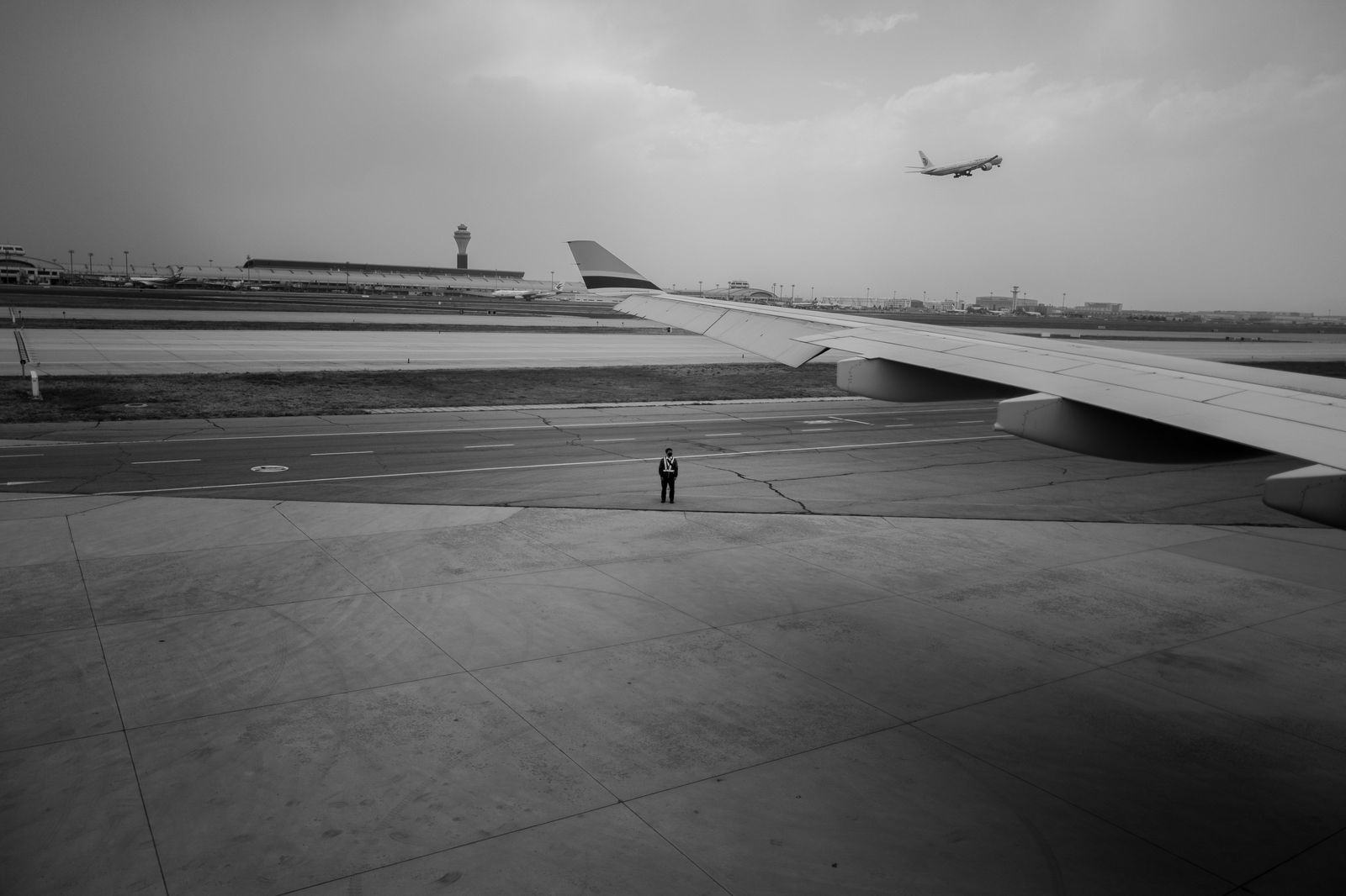 A black car waiting at the commercial pickup area outside an airport terminal