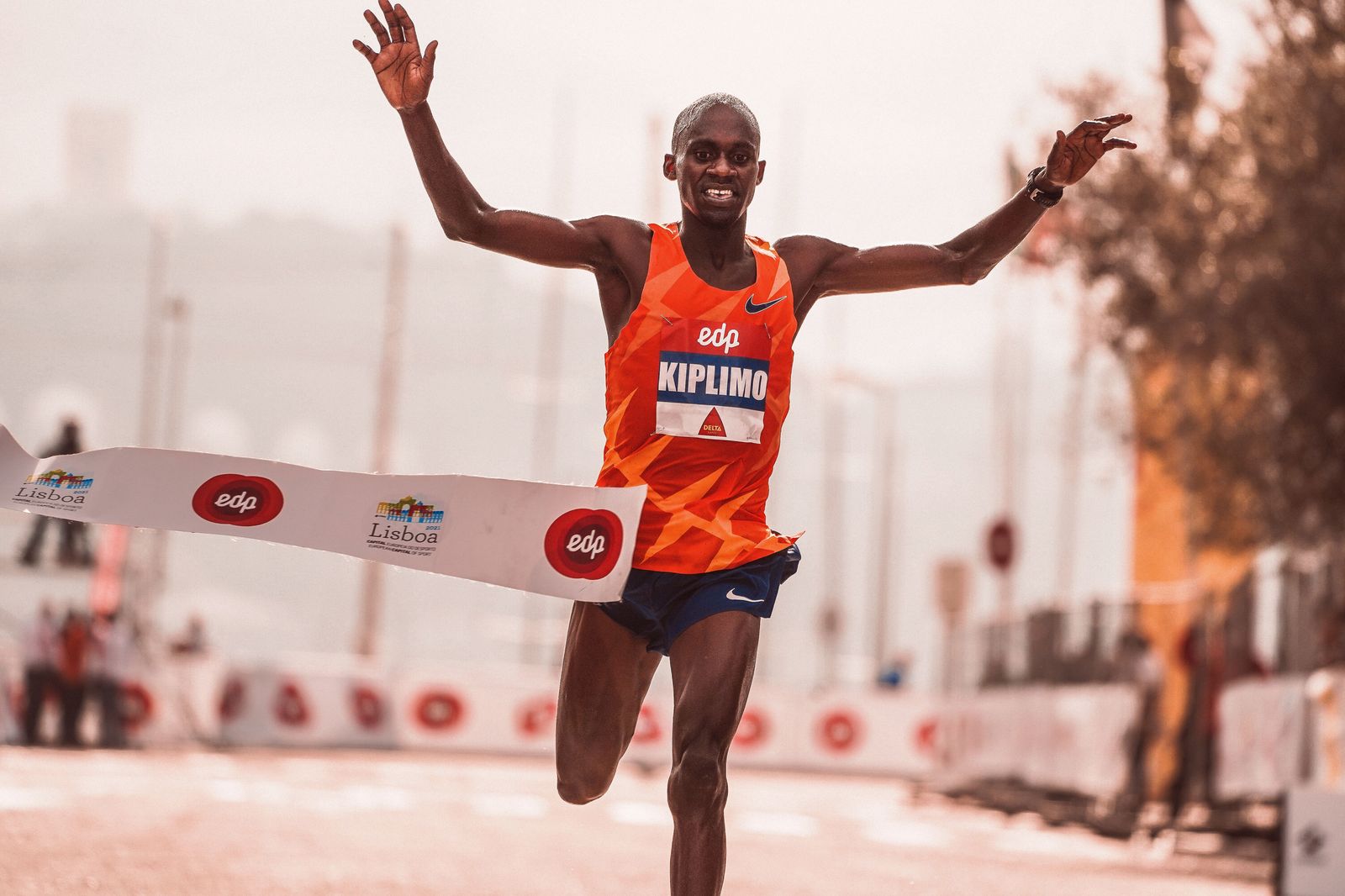 Runner wrapped in a foil blanket with a medal after crossing a road race finish line