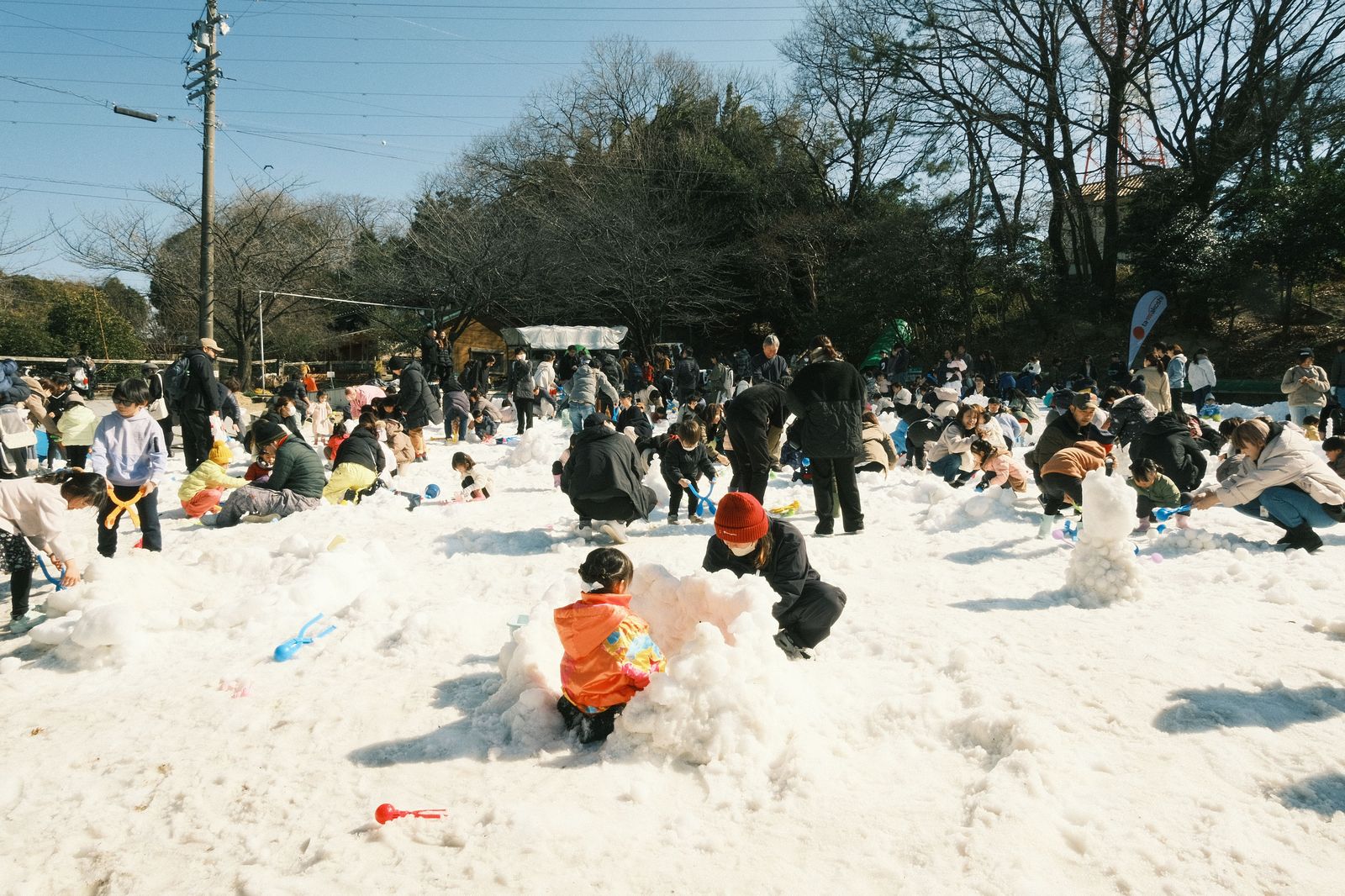 Family enjoying a snowy outdoor winter festival with children and sleds