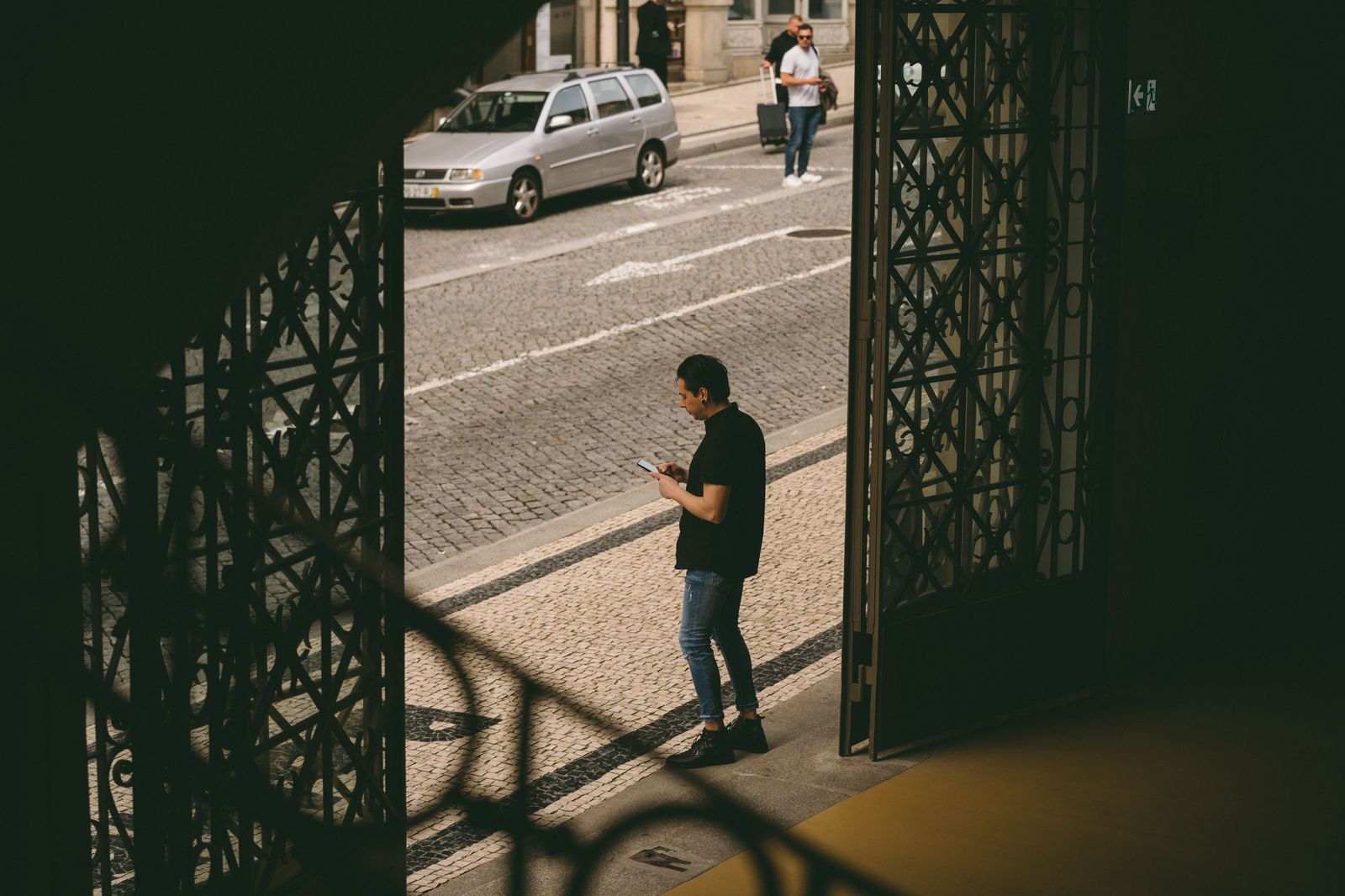 A chauffeur waiting beside a black car in the city