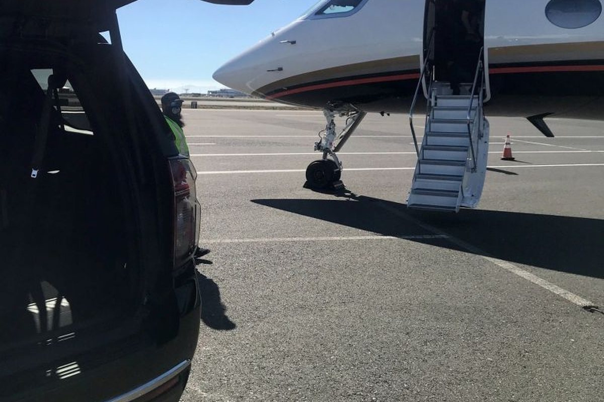 A HamiltonLimo.net SUV with the tailgate open beside a business jet on the ramp, ready for the luggage